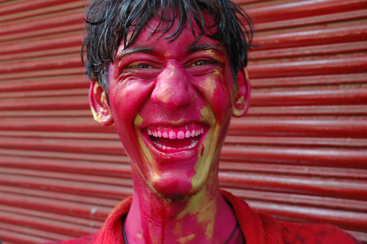 Young man with painted face laughing during Holi festival